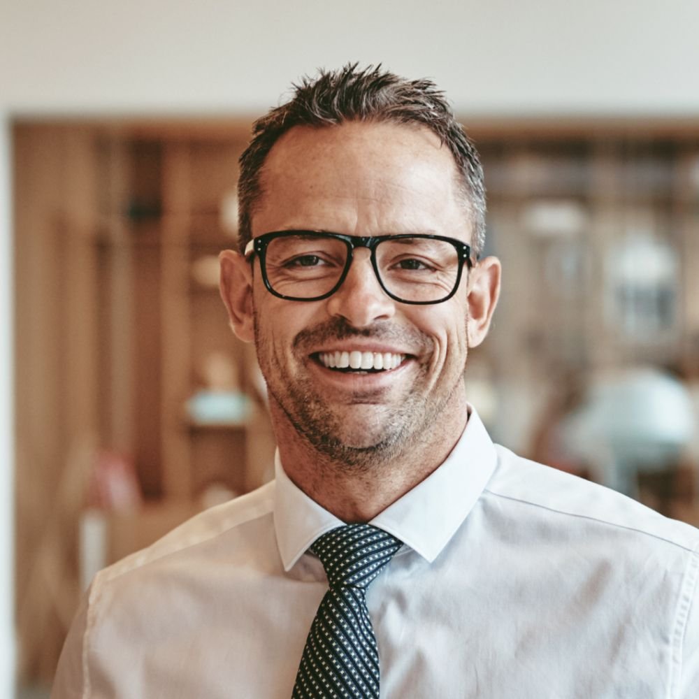 smiling mature businessman standing alone in an of Y89VGBD 1 1